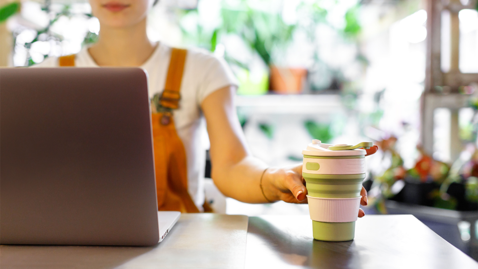 Women at laptop using a reusable mug