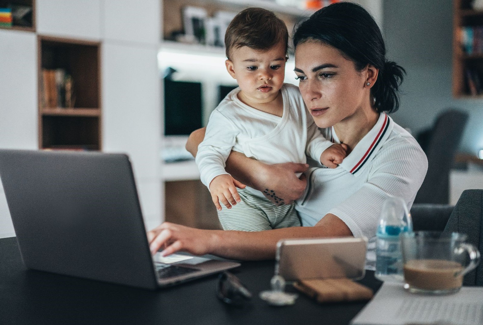 Woman working from home while holding her child