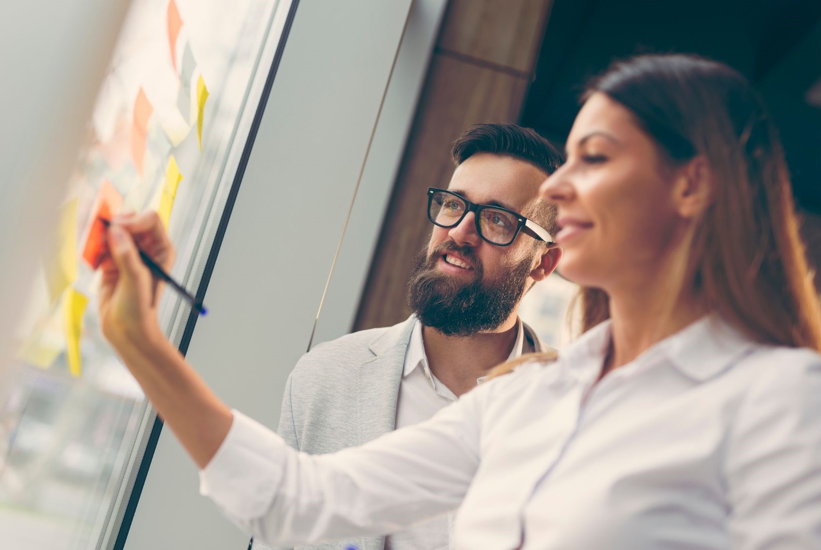 Man and woman brainstorming with sticky notes on a wall