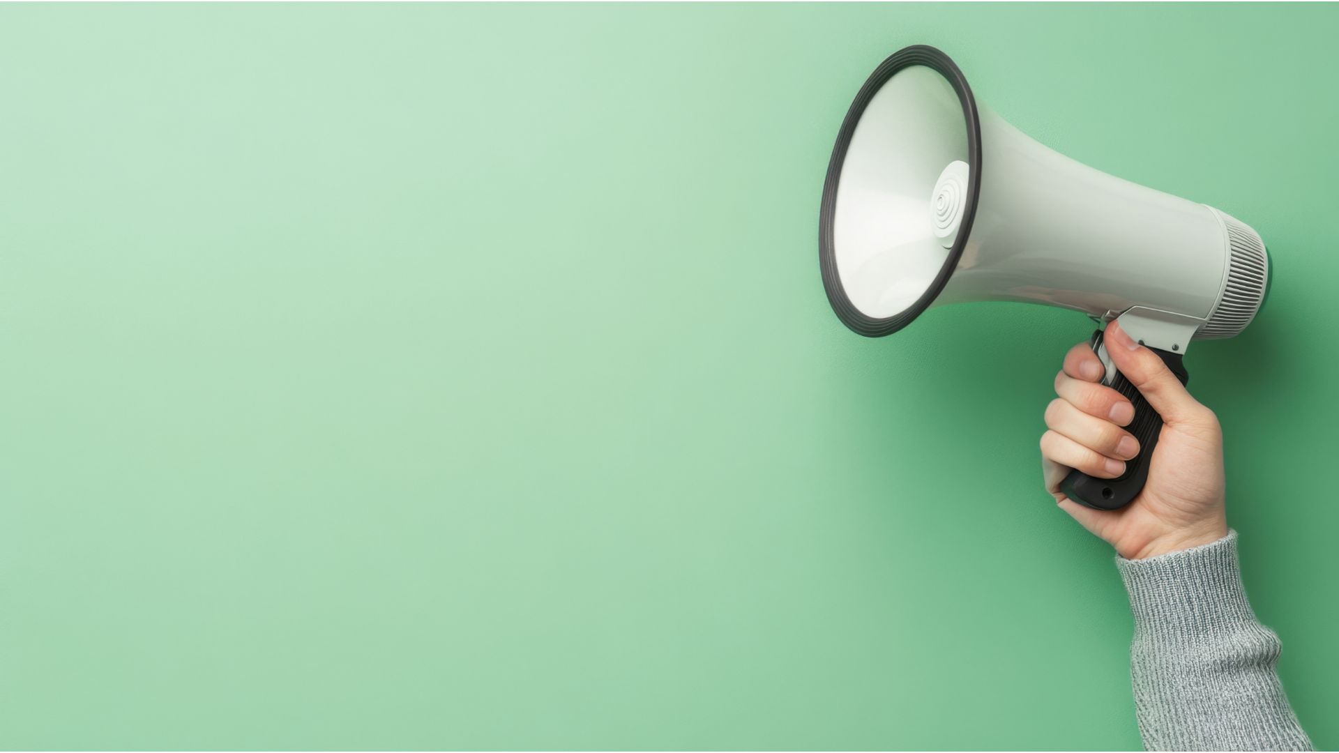 Hand holding megaphone against green background